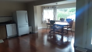 A dining area with a round table and chairs, a refrigerator, and a window with curtains. - SLOPES AND STREAMS (Searchmont)