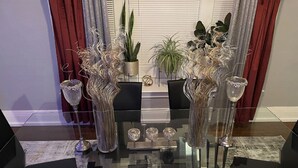 Een eettafel met zwarte stoelen, omringd door decoratieve vazen en planten.