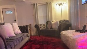 Een kamer met een rode karpet, een bank, een stoel en een bed.