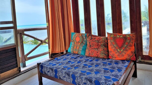 Una habitación con cama, ventanas amplias y vista al océano.