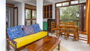 Una habitación con un sofá y una mesa de madera, además de un comedor con sillas de madera.