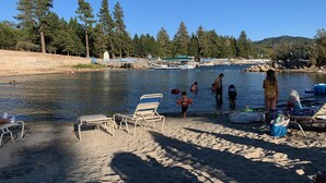 En strand ved søen med liggestole og en badebro.