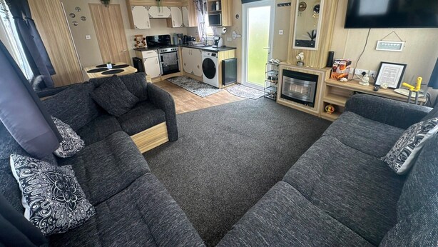 A compact RV interior with a kitchenette, two sofas, a flat-screen TV, and a fireplace. - Fluffy Caravan Sleeps 4, Pet-Friendly (Isle of Sheppey)