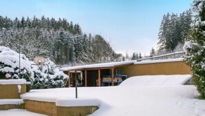 A snow-covered outdoor area with a building that has a wooden exterior and a glass door.