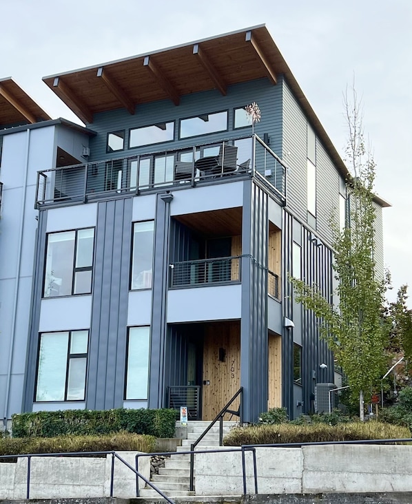 A modern multi-story building with a wooden upper floor and a grey lower floor.