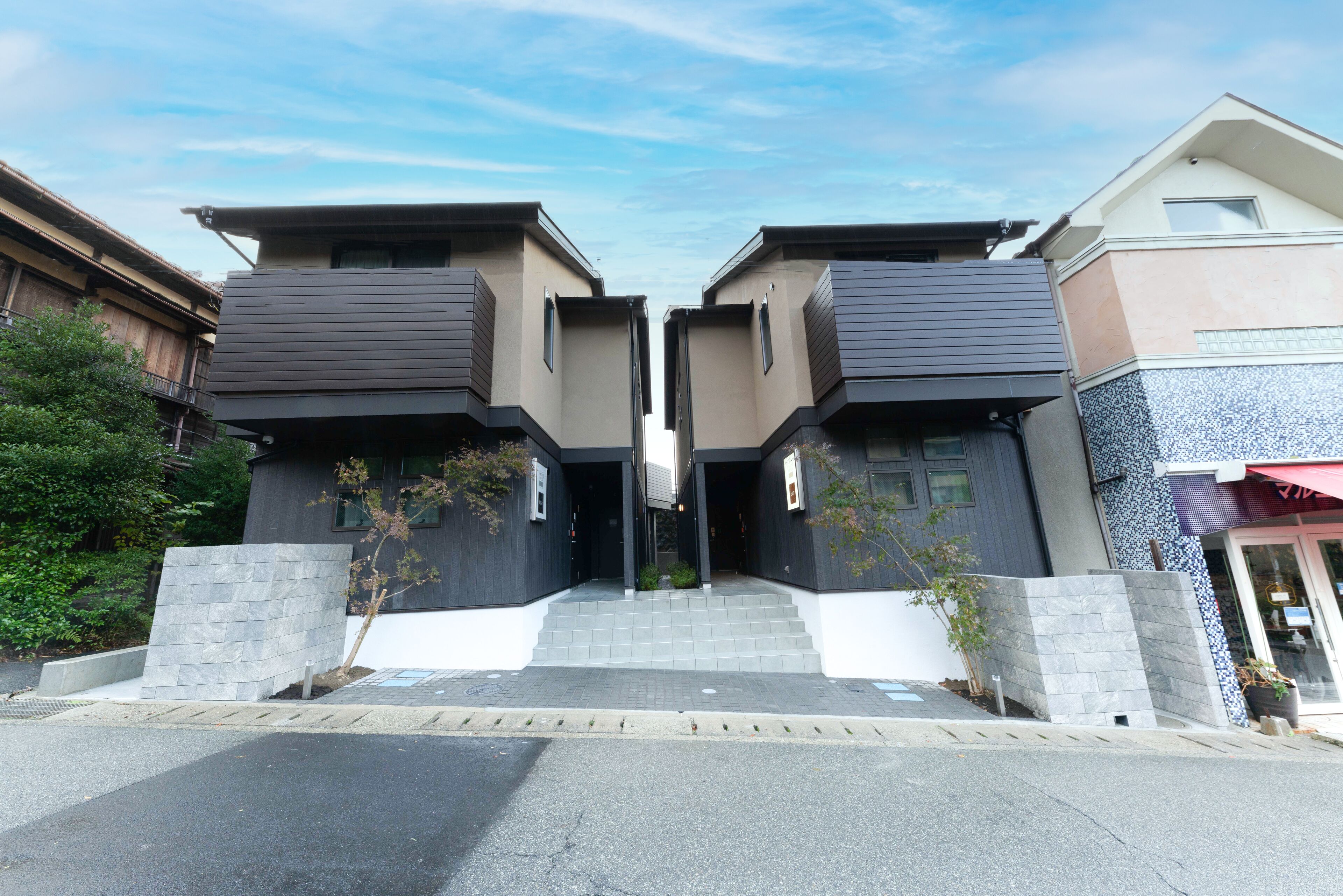 A modern building with a symmetrical facade, featuring two identical sections with a central entrance.