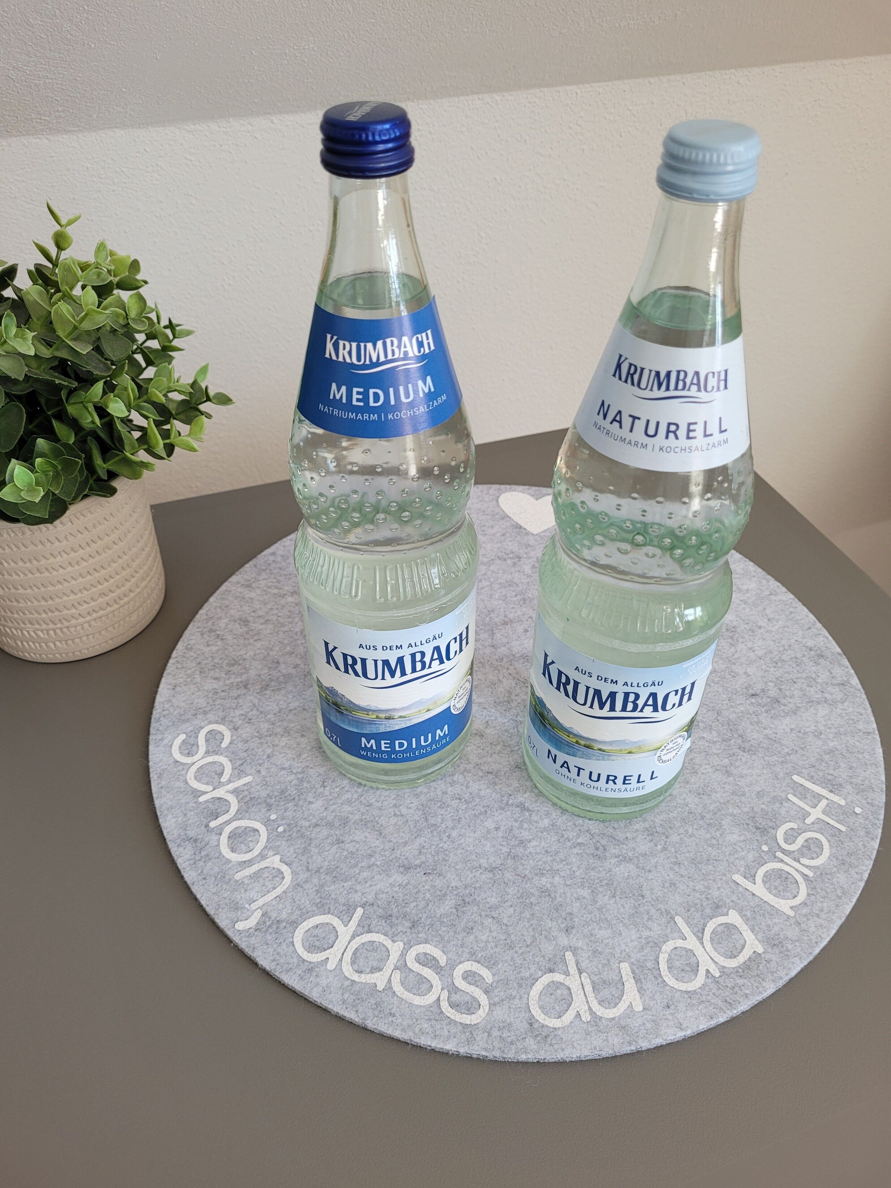 Two bottles of Krumbach water on a felt mat with text.