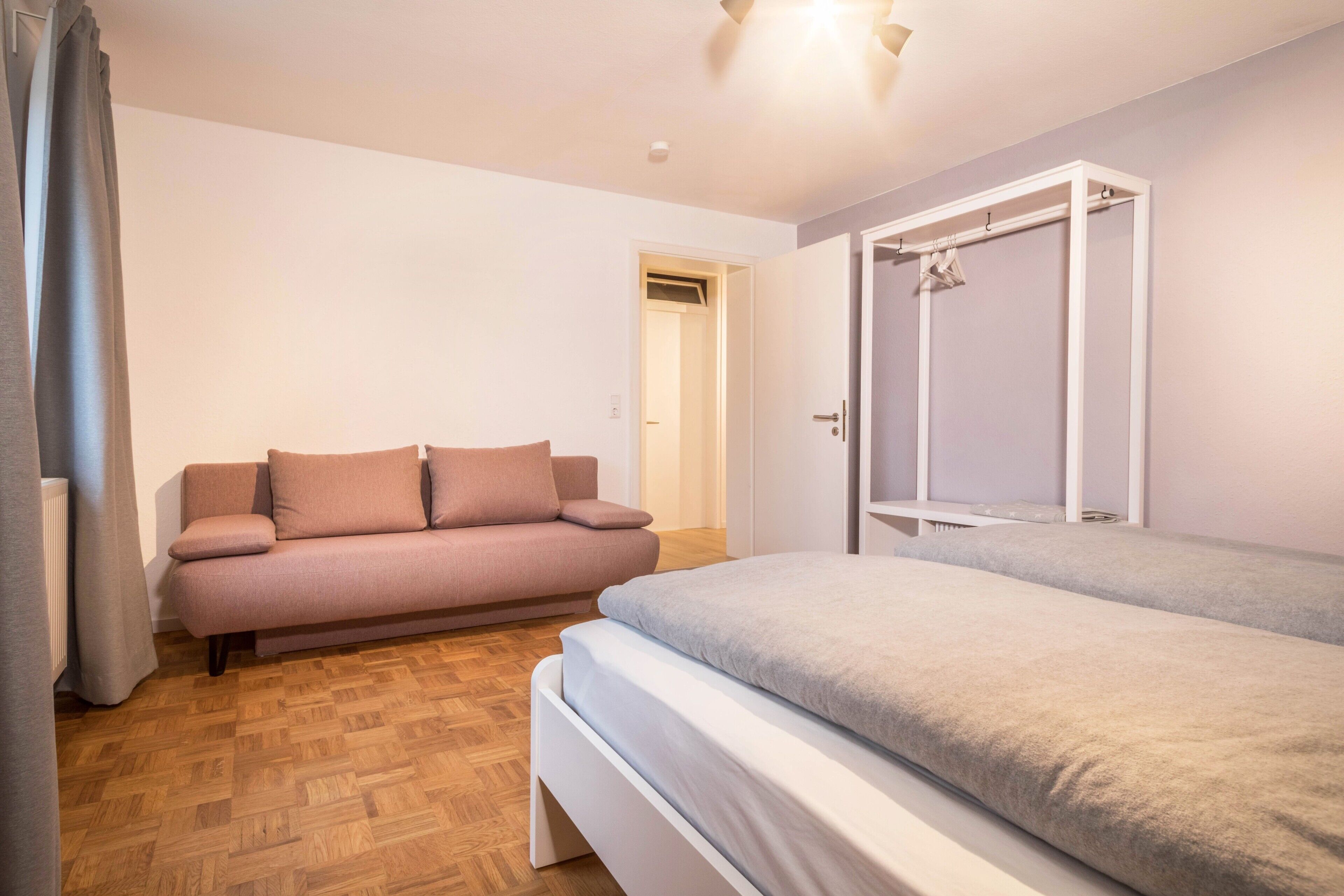 A bedroom with a bed, a sofa, and a wardrobe.