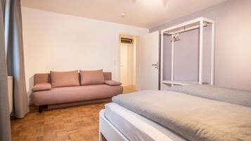 A bedroom with a bed, a sofa, and a wardrobe.
