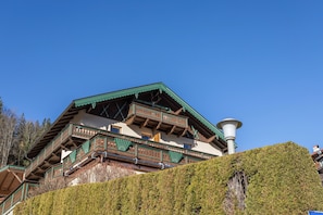 A traditional chalet with wooden balconies, a steep roof, and a chimney.
