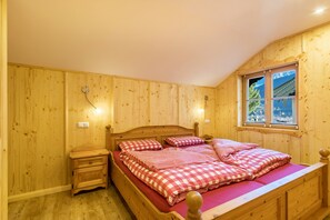 Une chambre à coucher aux murs lambrissés, avec un lit, une table de chevet et une fenêtre.