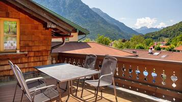 A wooden building with a balcony, a table, and chairs.