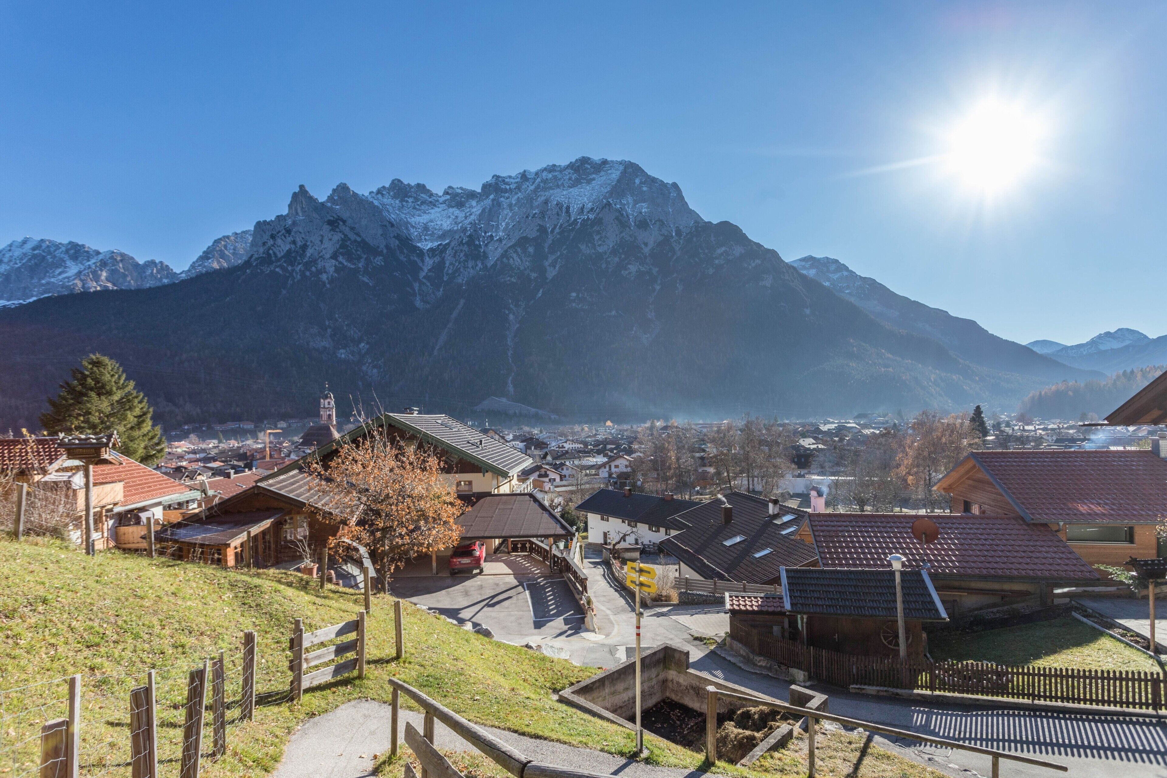 Ein Bergdorf mit traditionellen Häusern, einer asphaltierten Straße und freiem Blick auf die umliegenden Berge.
