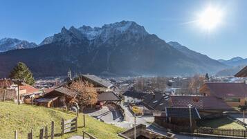 Ein Bergdorf mit traditionellen Häusern, einer asphaltierten Straße und freiem Blick auf die umliegenden Berge.