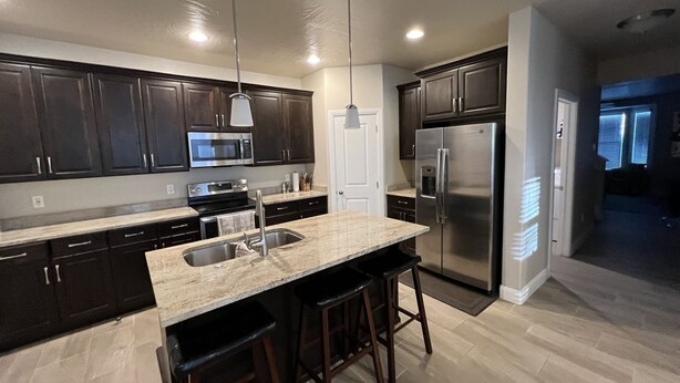 A modern kitchen with dark cabinets, stainless steel appliances, and a central island with bar stools.