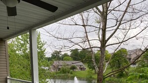 Un patio cubierto con una mesa y sillas de vidrio, con vista a un río y casas.