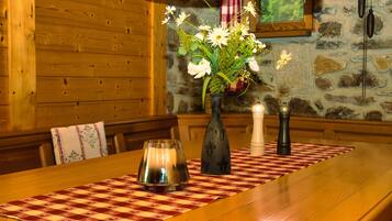 Een houten tafel met een geruit tafelkleed, een bloemenvaas, een kaars en een zoutvaatje.