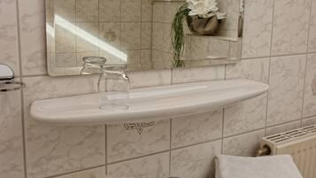 A bathroom with a white sink, a mirror, a towel rack, and a bottle of orange juice.