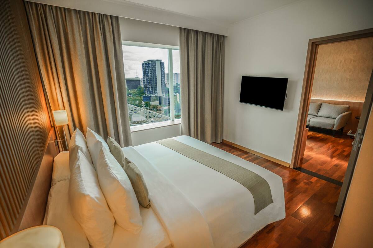 Habitación de hotel con una cama grande, televisión de pantalla plana, vistas a la ciudad y un espejo.