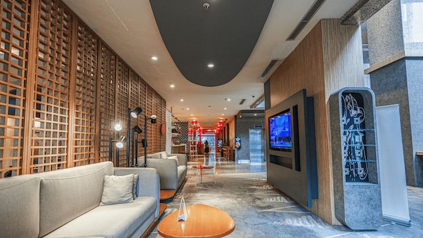 Um lobby moderno com um sofá, uma mesa de centro e uma tela de TV.