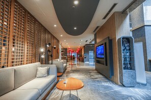 Un hall moderno con un sofá, una mesa de centro y una pantalla de televisión.