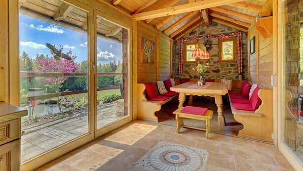 A wooden interior with a stone wall, a table, and benches.