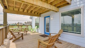 Una terraza de madera con mobiliario exterior, incluyendo sillas y bancos, y una zona cubierta con techo de madera.