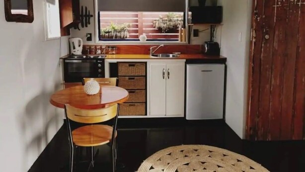 A compact kitchen with a dining table, chairs, and a view through the window.