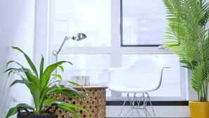A room with a large window, a white chair, a desk with a lamp, and several potted plants. - ⚡️ROOFTOP VIEWS⚡️The Helix⚡️Central🚶🏻‍♂️Walker’s paradise (Seattle)