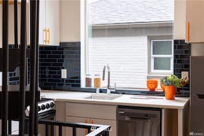 A modern kitchen with a white countertop, stainless steel appliances, and a window with blinds. - ⚡️ROOFTOP VIEWS⚡️The Helix⚡️Central🚶🏻♂️Walker’s paradise (Seattle)
