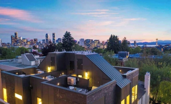 A modern building with a rooftop terrace, surrounded by a city skyline at dusk. - ⚡️ROOFTOP VIEWS⚡️The Helix⚡️Central🚶🏻♂️Walker’s paradise (Seattle)