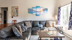 Ein Wohnzimmer mit Ecksofa, Couchtisch und Wandbild.