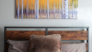 Ein Bett mit roter Decke, zwei Kissen und einem Holzkopfstück.