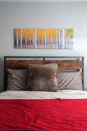 Relax in a serene bedroom with a comfortable bed, adorned with a stylish headboard and a beautiful painting of birch trees above.
