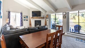 Ein modernes Wohnzimmer mit einer großen Couch, einem Holzessttisch und einem Kamin.