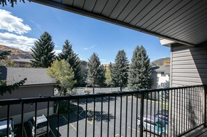 Enjoy a balcony with a view of the surrounding trees and parking area.