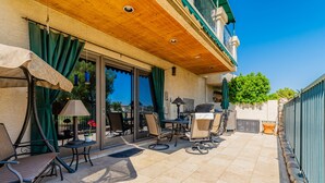 Une terrasse avec des meubles d’extérieur, un barbecue et un espace abrité doté d’un plafond en bois.