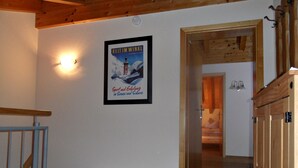 Ein Flur mit einer Holztreppe, einem gerahmten Poster an der Wand und einer Tür zu einem anderen Raum.