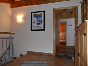 Ein Flur mit einer Holztreppe, einem gerahmten Poster an der Wand und einer Tür zu einem anderen Raum.