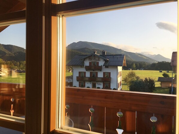 Blick auf ein Berghaus mit Balkon, umgeben von viel Grün und Bergen.