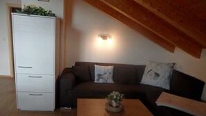 Ein Wohnzimmer mit einem dunkelbraunen Sofa, einem weißen Schrank und einem Couchtisch aus Holz mit einer Pflanze.