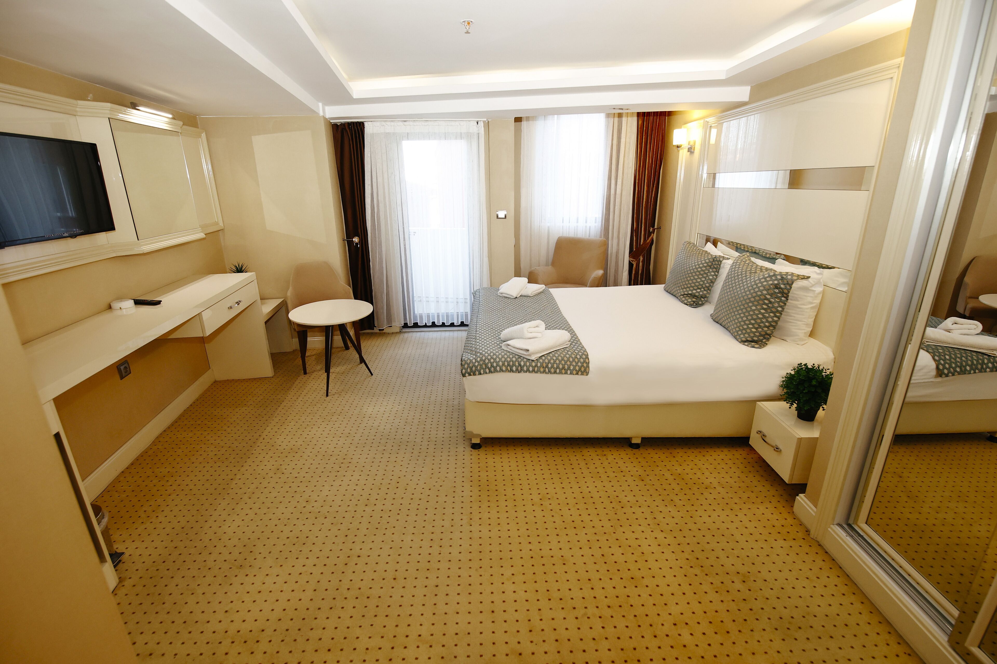Una habitación de hotel con una cama grande, un televisor, un escritorio y una mesita.
