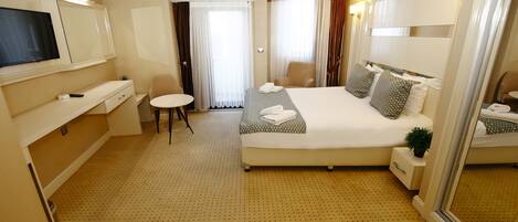 Una habitación de hotel con una cama grande, un televisor, un escritorio y una mesita.
