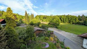 Ett bostadsområde med en asfalterad uppfart, en träkonstruktion och en välskött gräsmatta.