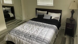 A bedroom with a bed, a nightstand, a lamp, and a window with blinds. - 3 bedroom House in a quiet neighborhood (Orlando)
