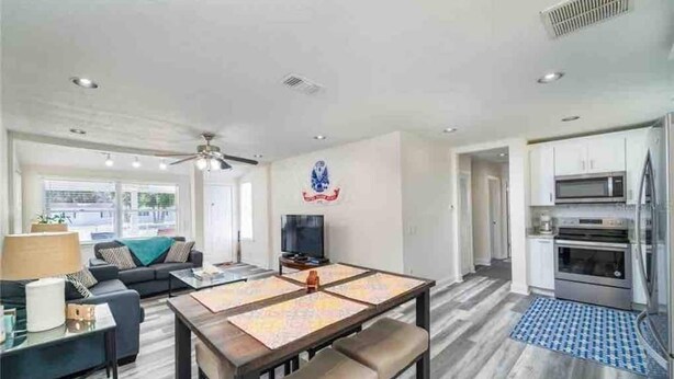 A modern living room with a dining table, sofa, and TV. - 3 bedroom House in a quiet neighborhood (Orlando)