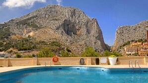 A swimming pool with a lifebuoy and a towel rack, set against a backdrop of rocky mountains and a clear sky. - Casa Rousell - Altea, Costa Blanca (Altea)