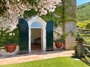 A rustic entrance with a white archway, green shutters, and a garden view.