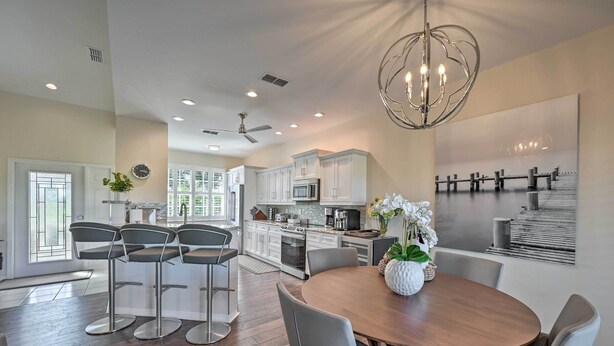 A spacious kitchen with white cabinets, a microwave, and a dining area with a wooden table and four chairs.