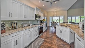 A spacious kitchen with white cabinets, granite countertops, and a large island.